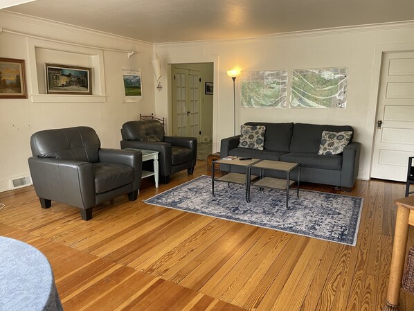 A living room with a dark leather sofa, two armchairs, a coffee table, and a rug. There are framed pictures on the wall and a map on the wall. - Family Friendly, Close To Downtown, Best views of Longs Peak and the Range (Estes Park)