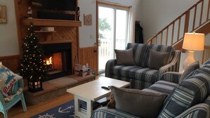 A cozy living room with a fireplace, striped sofas, a small table, and a Christmas tree. - Fabulous sunsets! (Kitty Hawk)