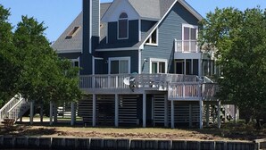 A two-story house with a balcony, a chimney, and a dock extending into a body of water. - Fabulous sunsets! (Kitty Hawk)