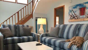 A living room with striped sofas, a small white table, and a dog lying on one sofa. - Fabulous sunsets! (Kitty Hawk)