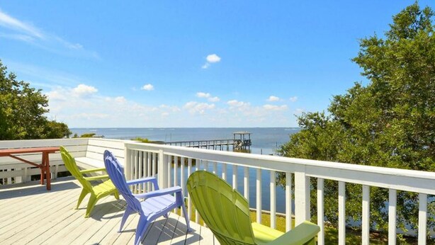 A deck with colorful chairs overlooking a body of water and a pier. - Fabulous sunsets! (Kitty Hawk)