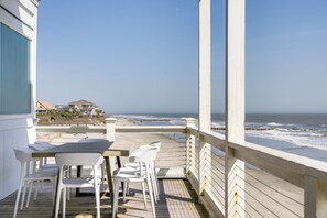 A wooden deck with a table and chairs overlooking the ocean.