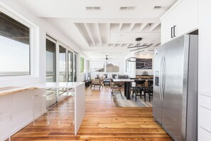 A modern kitchen with a wooden floor, white cabinetry, and a stainless steel refrigerator.
