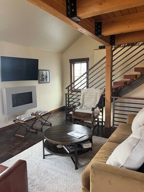 A living room with a fireplace, a sofa, a coffee table, a TV, and a staircase.