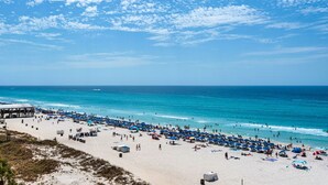 Una spiaggia con un molo, ombrelloni e bagnanti.