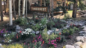 A sign for Timbernest with a garden in front. - Peak 9 - Walk to Ski Slopes & Main St - Hot Tubs, Pool, Fireplace (Breckenridge)