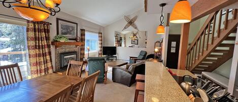 A spacious living area with a fireplace, dining table, and kitchen counter.