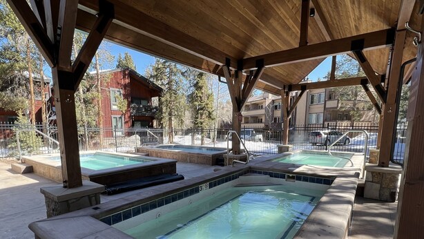 A covered outdoor swimming area with multiple hot tubs and a wooden deck. - Peak 9 - Walk to Ski Slopes & Main St - Hot Tubs, Pool, Fireplace (Breckenridge)