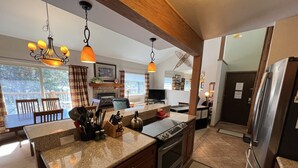 A kitchen with granite countertops, a stove, and a refrigerator. There is a dining table with chairs and a chandelier. - Peak 9 - Walk to Ski Slopes & Main St - Hot Tubs, Pool, Fireplace (Breckenridge)