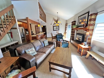 Living room with open floor plan and high ceilings, fireplace, and deck.