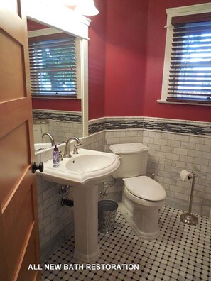 Classic bathroom with a pedestal sink, toilet, bidet, and black and white tile accents.