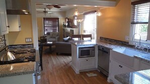 A compact kitchen with a stove, oven, and dishwasher. There is a dining area with a table and chairs. - 1927 Restored Downtown Phx Historic Bungalow close to Medical & Sports. (Phoenix)