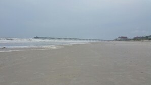 Ein Strand mit einem Steg, der sich ins Meer erstreckt.