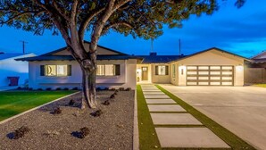 A modern two-story house with a garage, a well-maintained lawn, and a tree in the front yard.