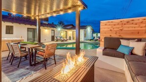 A covered outdoor area with a pool, a fire pit, and seating.