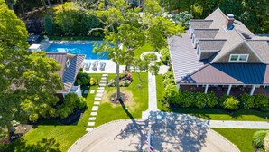 An aerial view of a residential area with a swimming pool, a house with a sloped roof, and a flagpole.