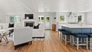 A spacious living area with a fireplace, a kitchen with a large island, and a dining area.
