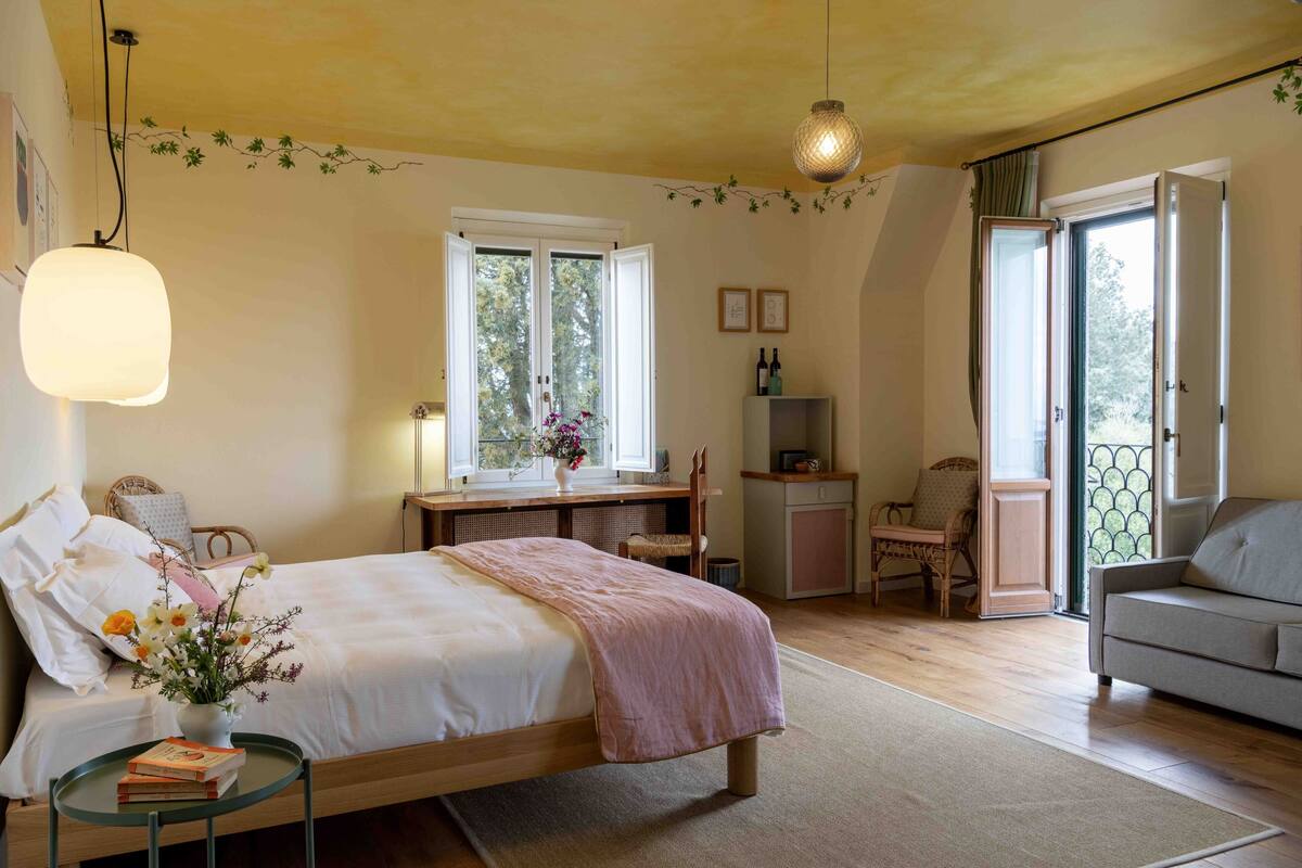 Un dormitorio con cama, mesita de noche y ventana con vistas a árboles.