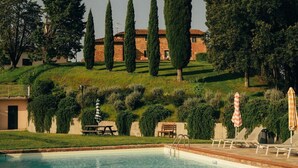 Une piscine dont l’eau est d’un bleu limpide, entourée de haies soigneusement taillées et de grands arbres.