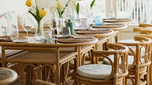 Un restaurant avec des chaises et des tables en osier, décorées de verres et de fleurs jaunes.