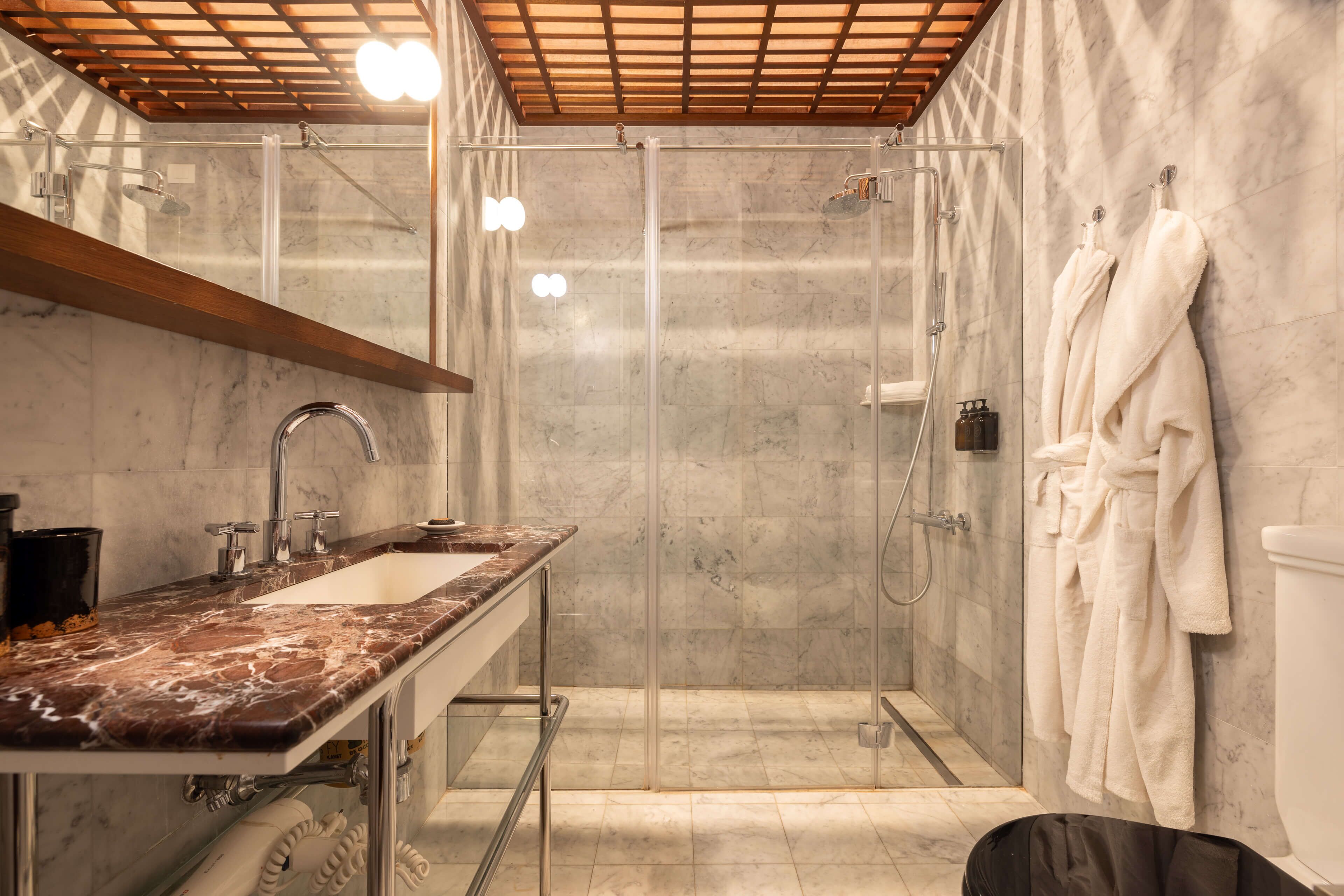 A modern bathroom with a glass-enclosed shower, a marble sink, and white towels.