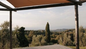 Une terrasse en bois avec un auvent, des serviettes, des bougies et une vue sur la campagne.