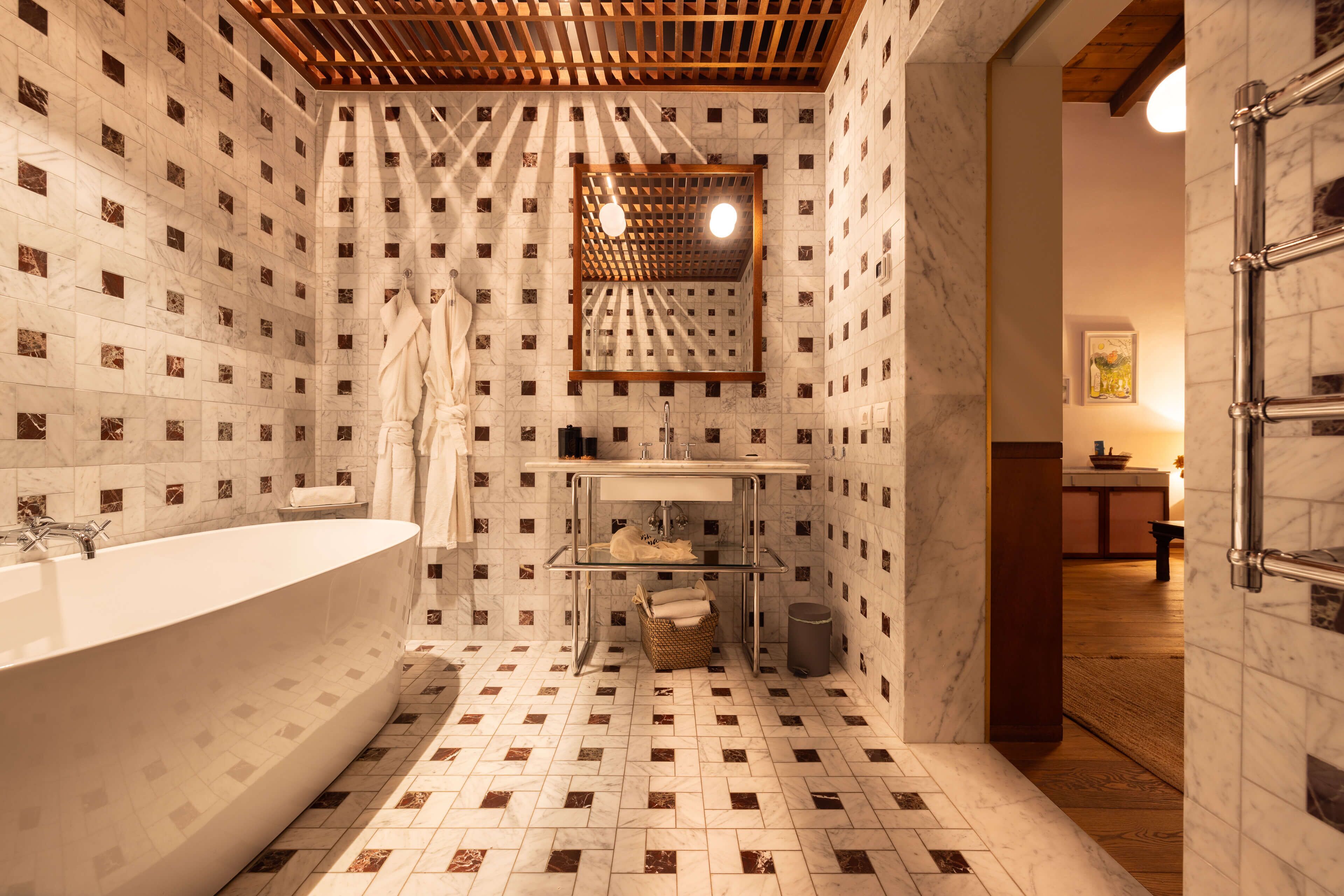 Ein modernes Badezimmer mit einer freistehenden Badewanne, einem Waschtisch mit Spiegel und einer Holzbalkendecke.