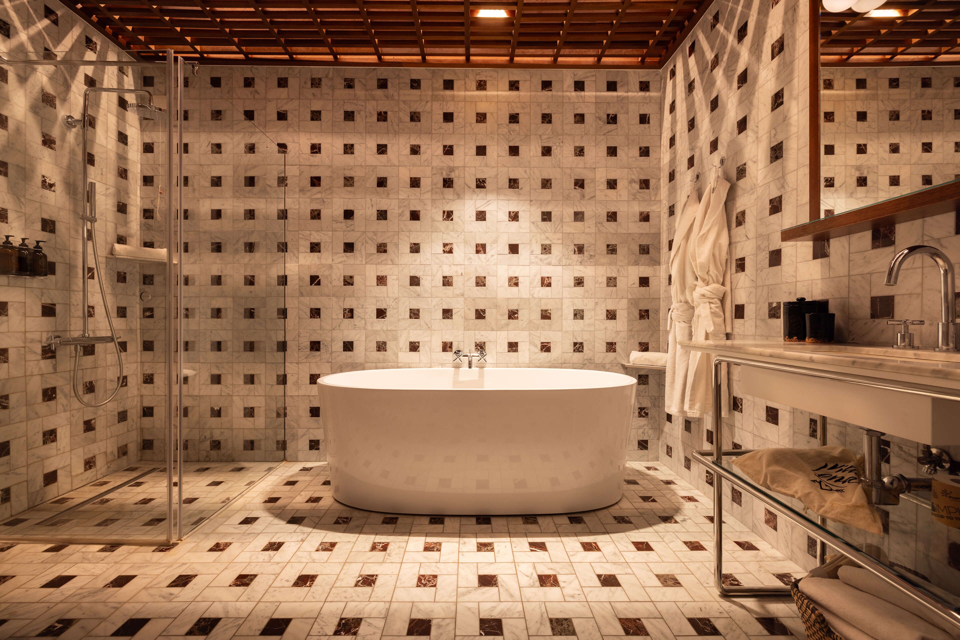 Un baño moderno con una bañera independiente, una ducha con cerramiento de vidrio y suelo de mármol.