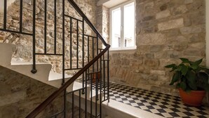 A staircase with stone walls, a black and white checkered floor, and a window with white frames. - Luxury Apartment Matkovic (Split)