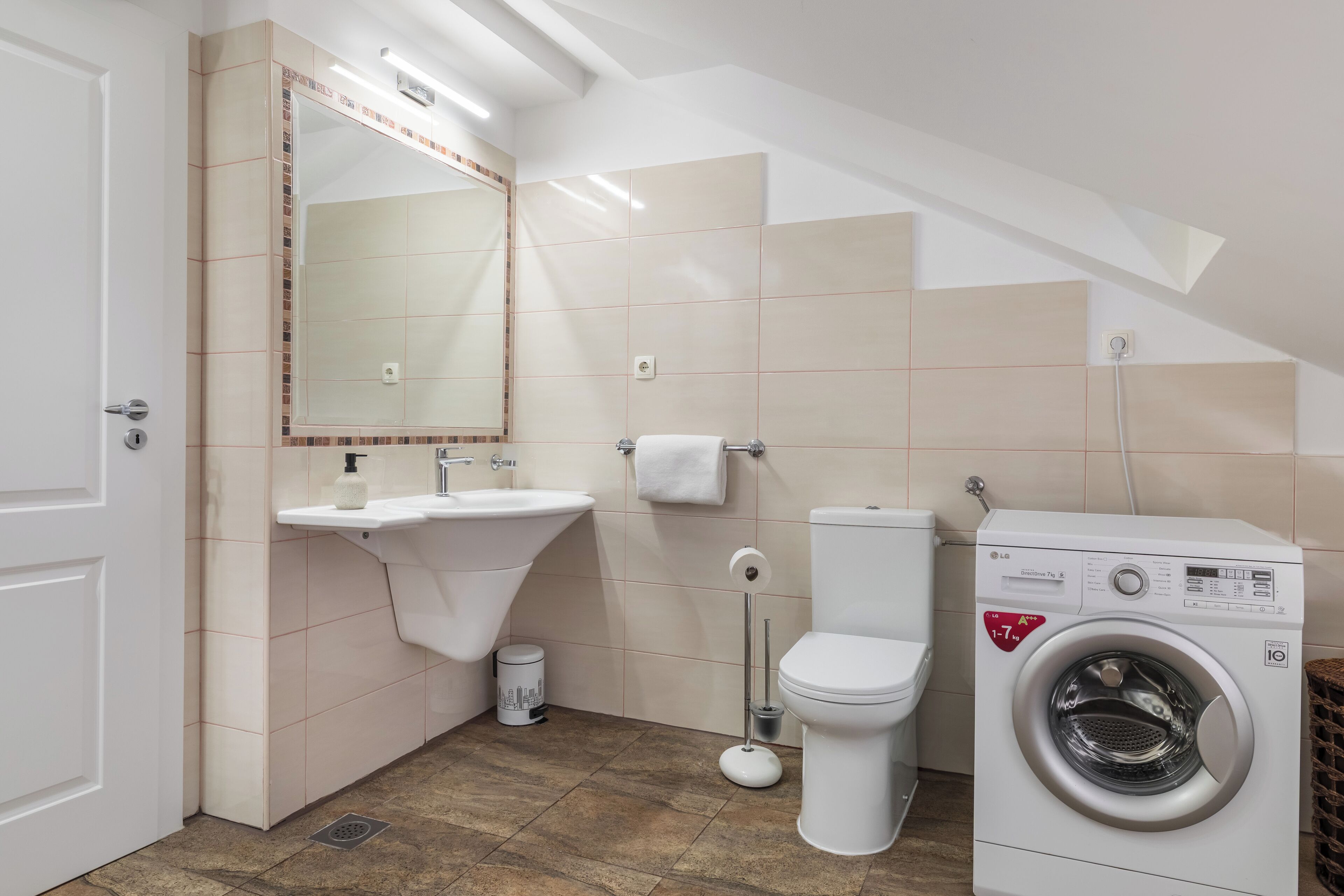 Une salle de bain équipée d’un lavabo, de toilettes et d’un lave-linge.