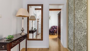 A hallway with a wooden floor, a console table with a lamp, a mirror, and a patterned wall. - Luxury Apartment Matkovic (Split)