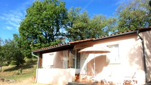 A single-story house with a patio area, a covered seating area with chairs and an umbrella, and a number '15' on the wall. - Les Sentiers du Causse  (Lentillac-du-Causse)