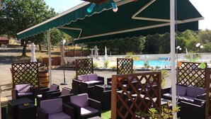 An outdoor seating area with wicker furniture and umbrellas, overlooking a swimming pool. - Les Sentiers du Causse  (Lentillac-du-Causse)