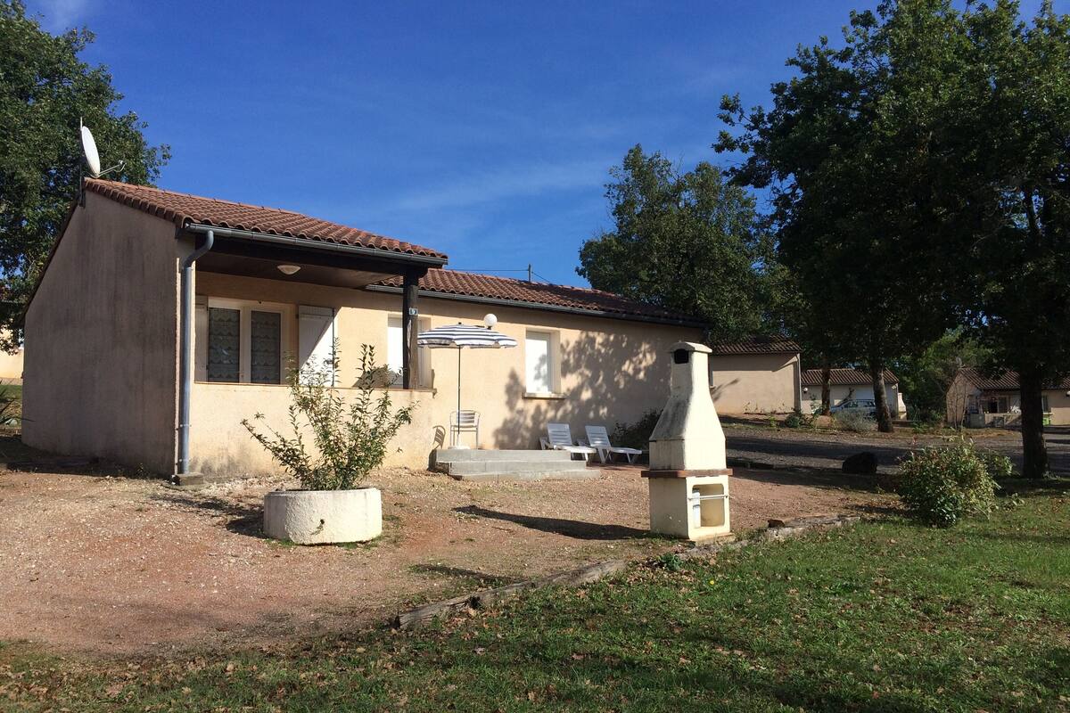 Ein eingeschossiges Haus mit Ziegeldach, Satellitenschüssel und Grill im Garten.