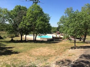 A pool area surrounded by trees, with a building in the background. - Les Sentiers du Causse  (Lentillac-du-Causse)