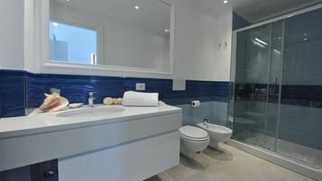 Een moderne badkamer met een grote spiegel, een witte wastafel en een douche met glazen wanden.
