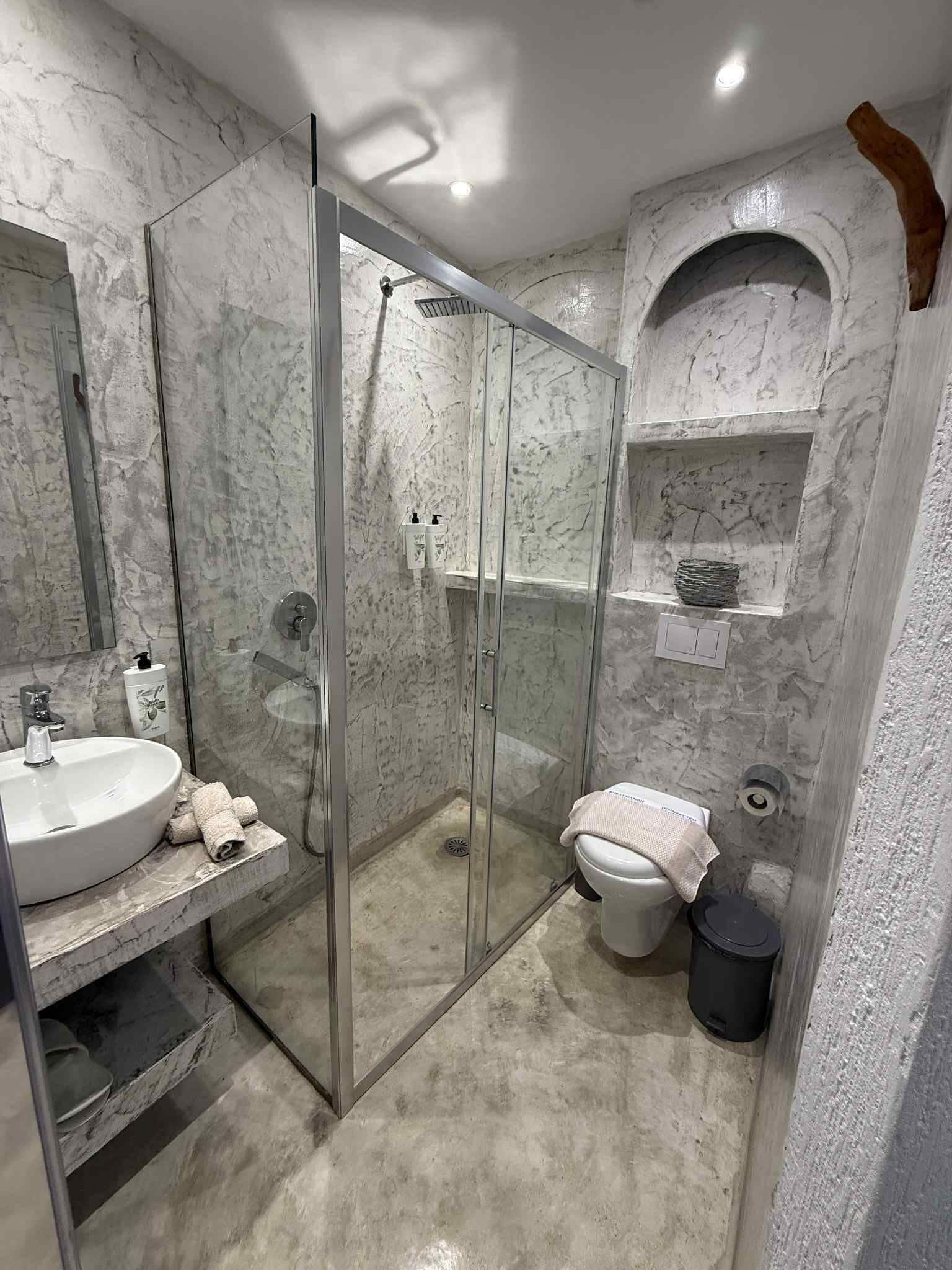 Un baño con ducha de vidrio, un lavabo blanco y un inodoro.
