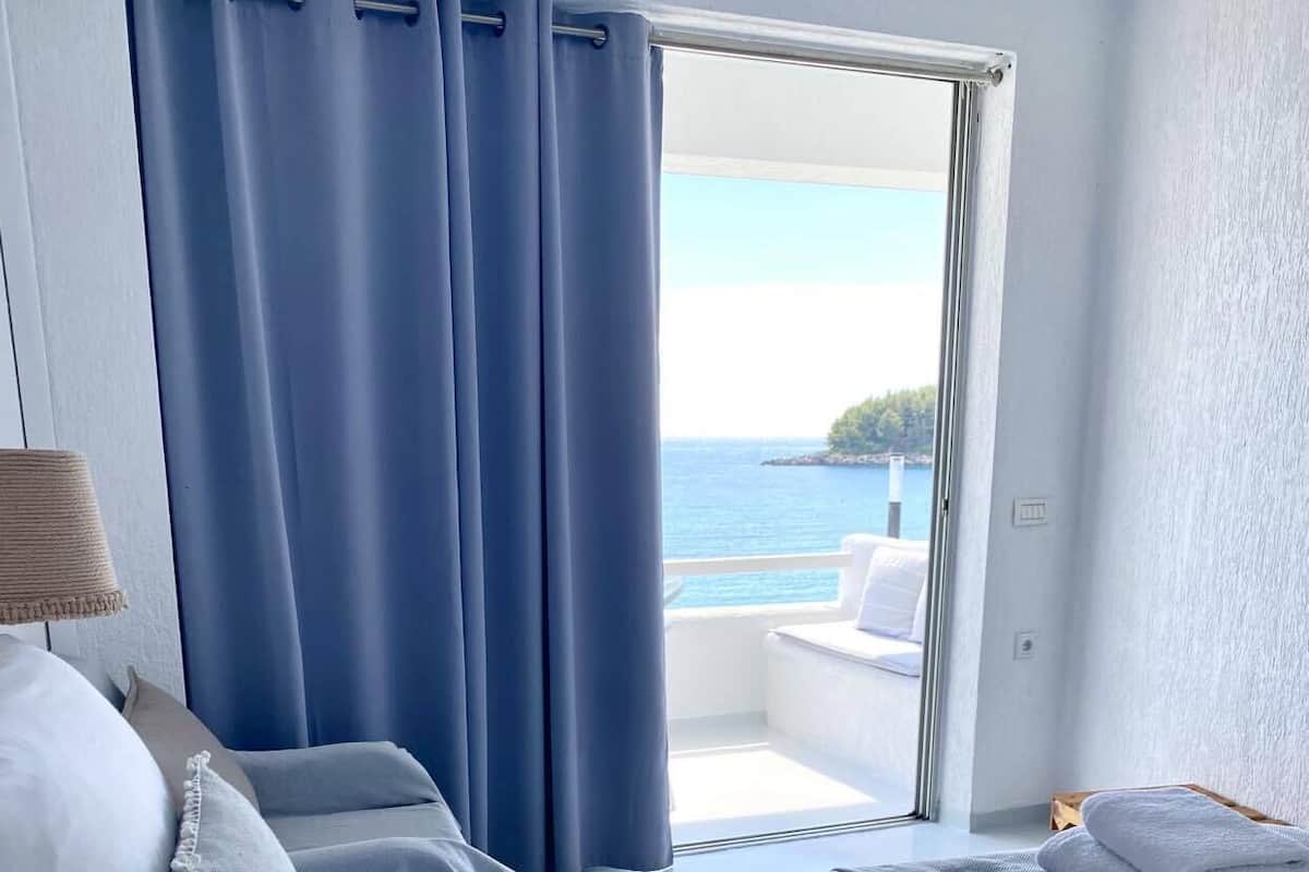 Ein Hotelzimmer mit Bett, einem Sessel, Meerblick und einem Balkon.