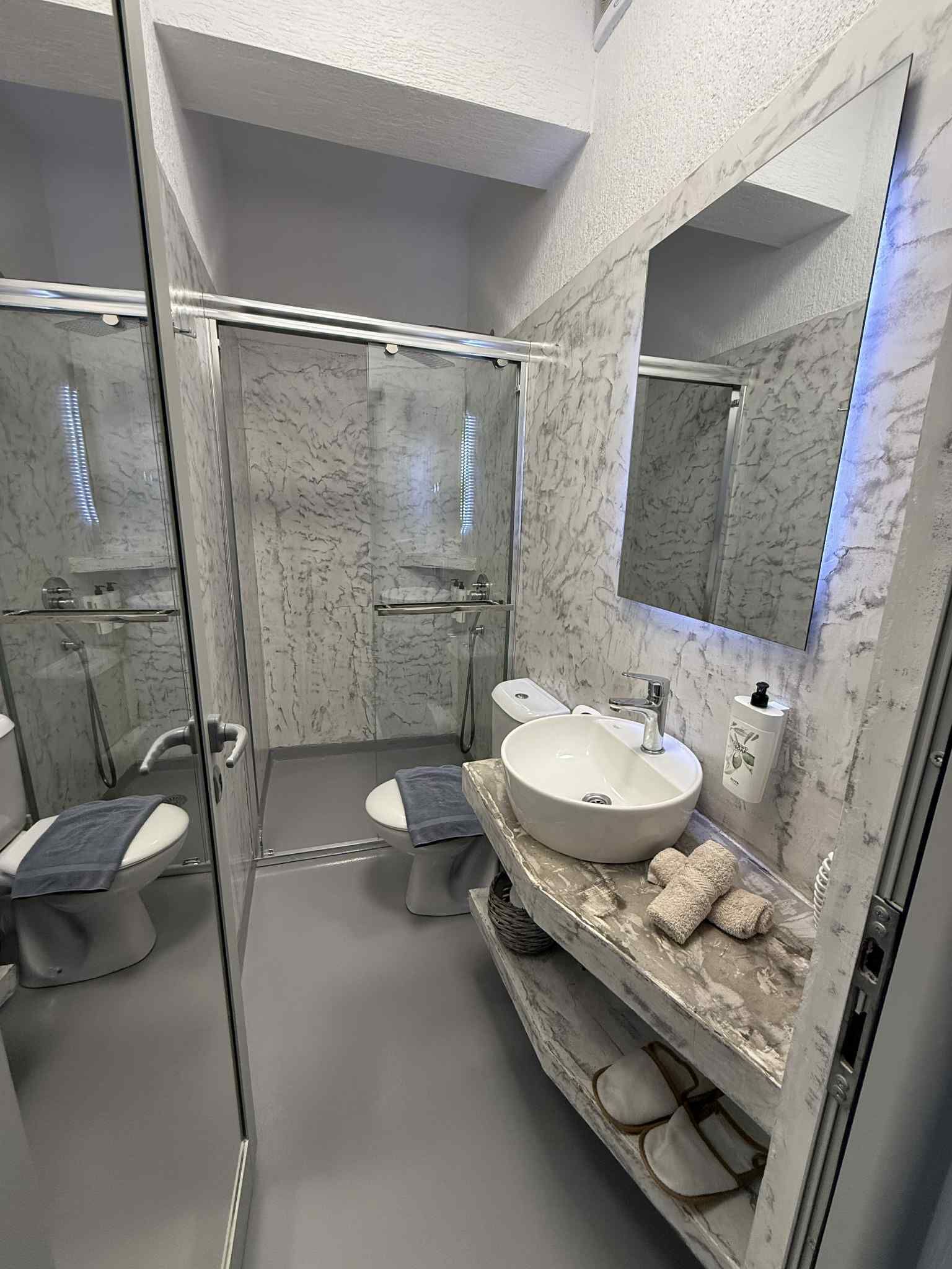 A modern bathroom with a glass-enclosed shower, a white sink, and a large mirror.