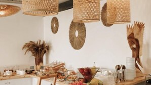 Un buffet agrémenté de luminaires en rotin suspendus, d’une variété de plats et d’œuvres d’art décoratives murales.