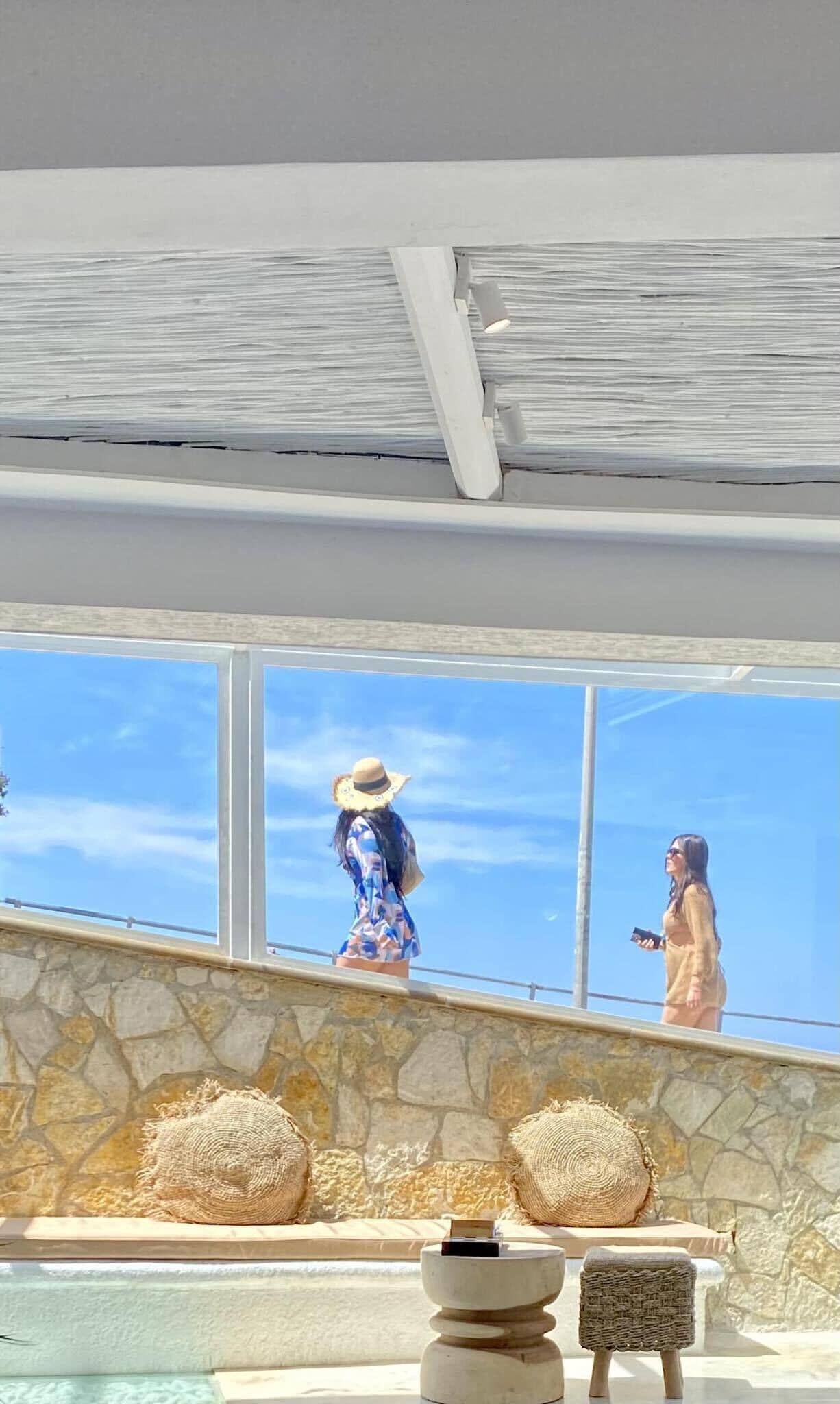 A modern interior with a stone wall and a large window overlooking a clear sky.