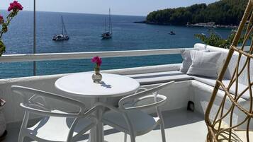 Un área de estar al aire libre con una mesa y sillas, con vista al mar y embarcaciones.