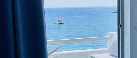 A balcony with a view of the sea and a sailboat.