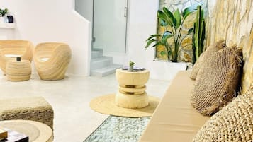 Un intérieur moderne avec un plafond en verre, un mur en pierre et un espace salon doté de meubles en osier.