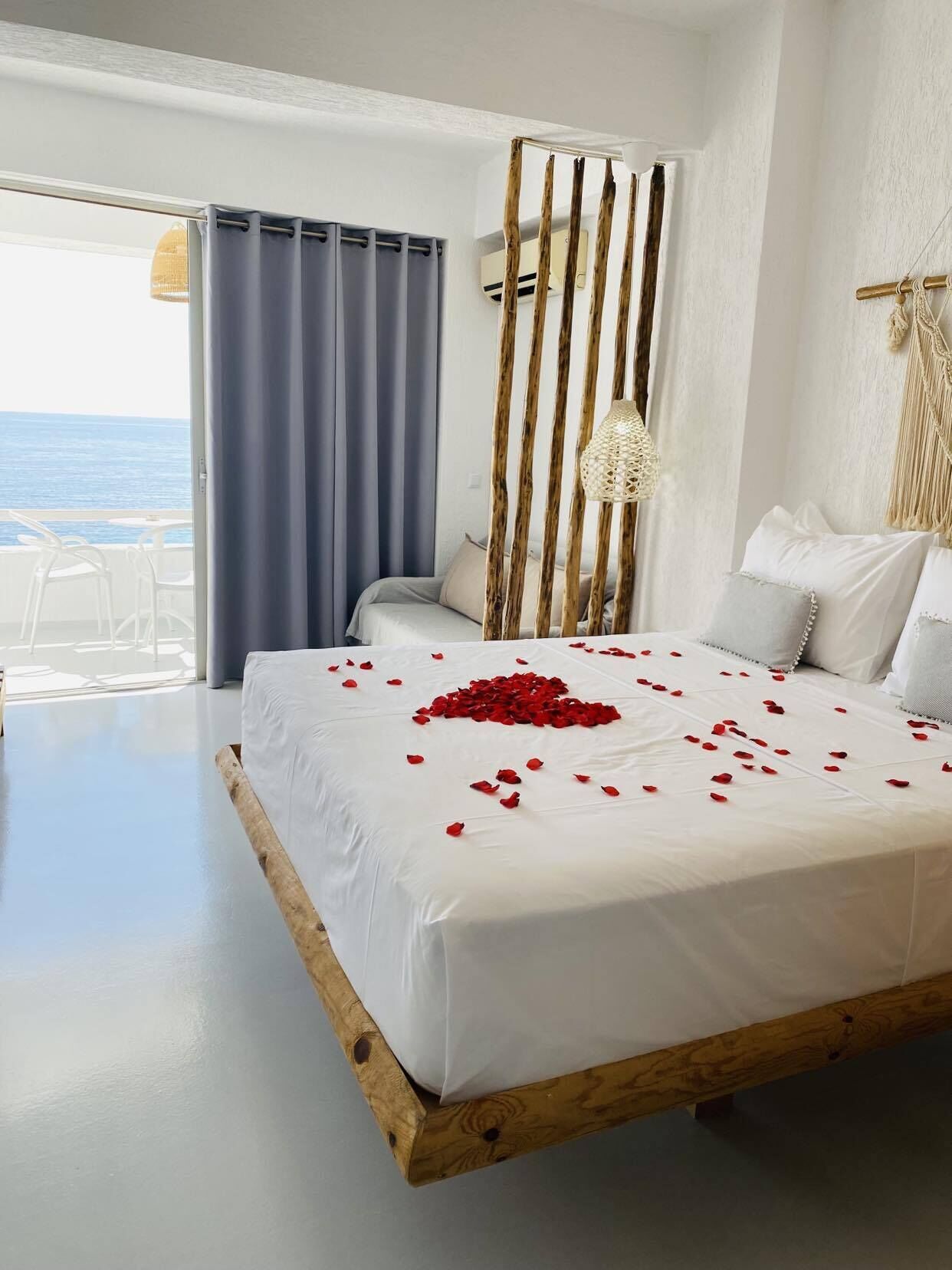 A bedroom with a bed, a view of the sea, and a balcony.