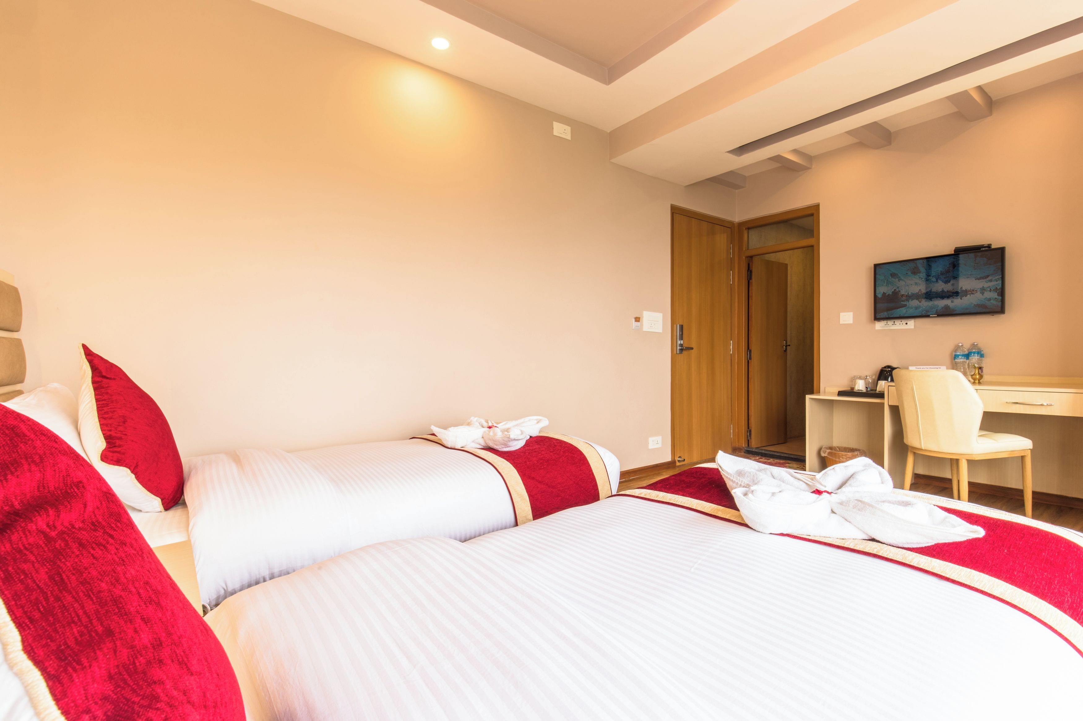 A hotel room with a bed, a desk, a chair, and a painting on the wall.