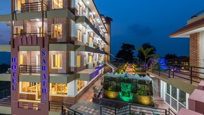 A multi-story hotel with a modern design, featuring balconies, a well-lit entrance, and a landscaped garden area. - Hotel Sarathi (Dhulikhel)