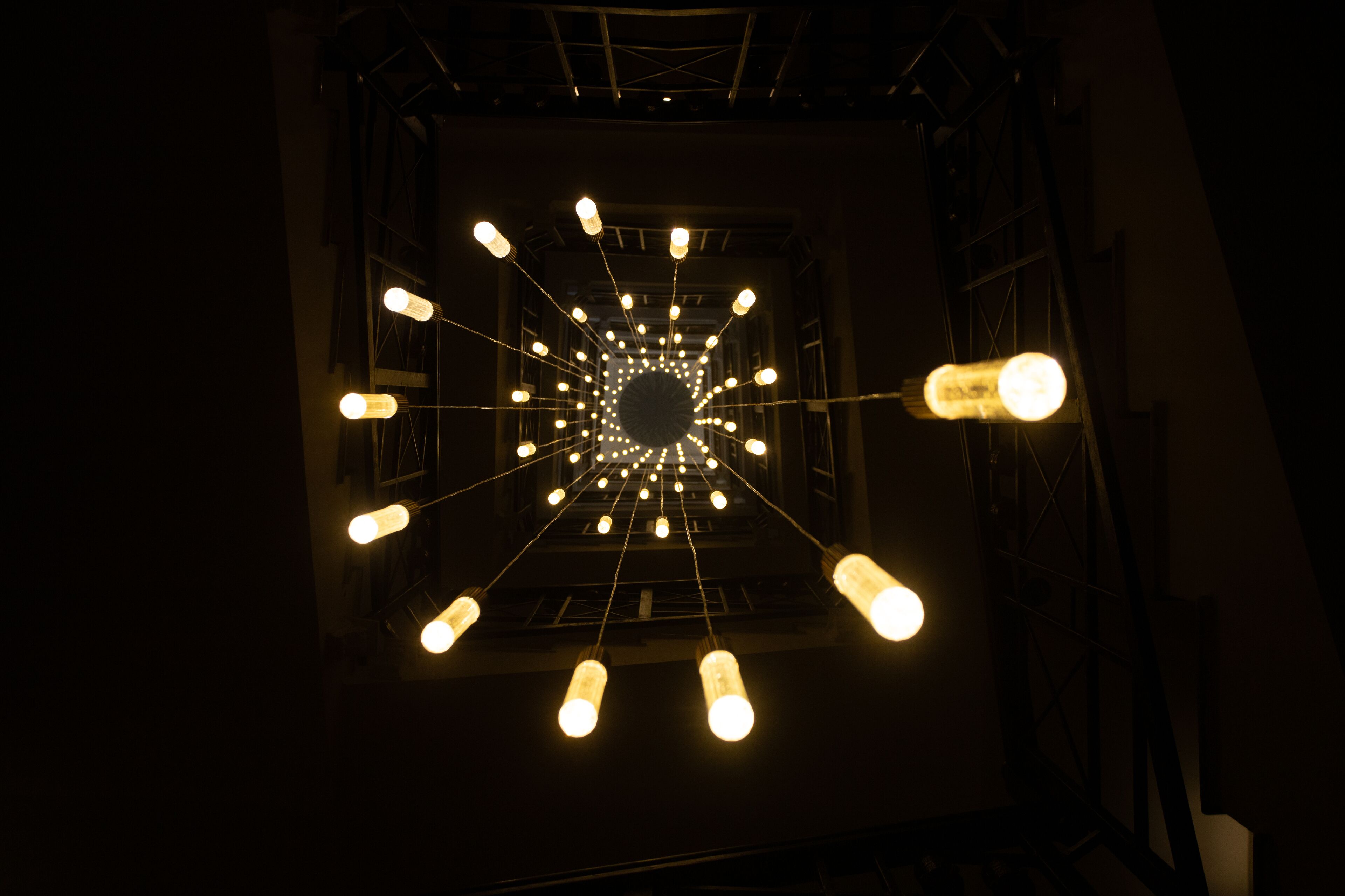 Una instalación de luces geométricas con un diseño circular central y líneas que irradian desde él.