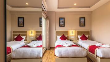 Une chambre d’hôtel avec deux lits, chacun agrémenté d’un coussin rouge, de lampes de chevet et d’œuvres d’art encadrées accrochées aux murs.