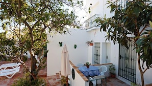 A small outdoor patio with a table and chairs, surrounded by potted plants and a white wall. - Hostal La Posada de Conil (Conil de la Frontera)